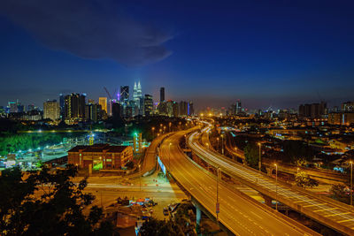 Distant view of petronas towers against sky in illuminated city at dusk