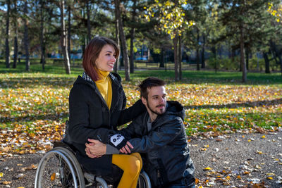 Young couple sitting in park during autumn