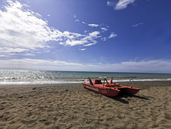 Fishing boat on beach against sky