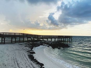 Pier over sea against sky during sunset