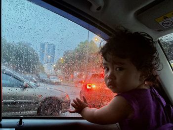 Girl looking through wet window during rainy season