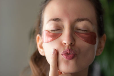 Romantic young woman with pink patches in heart shape under eyes, send air kiss. valentines day.