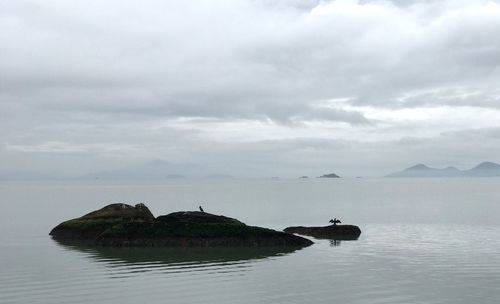 Scenic view of rocks in sea against sky