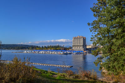 Scenic view of river by buildings against blue sky