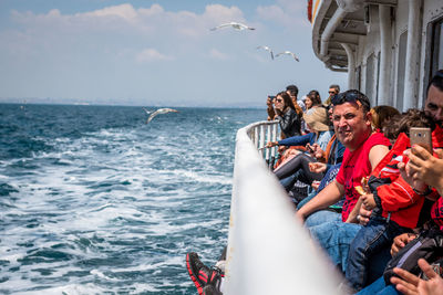 People photographing boats in sea against sky