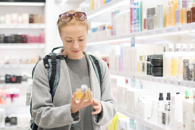 Young man holding bottle while standing at store