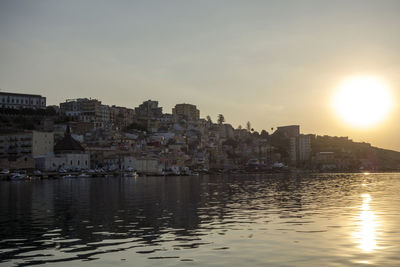 View of sea by town against sky during sunset