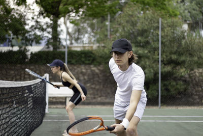 Side view of man and woman tennis couple concentrating on playing trying to hit the ball.