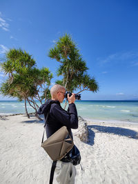Side view of man photographing at beach