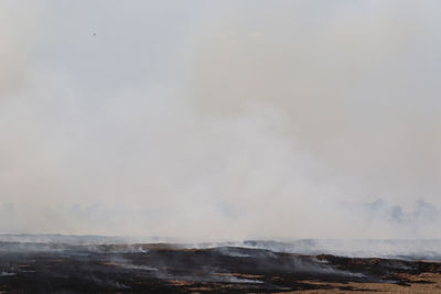 Smoke emitting from volcanic landscape against sky