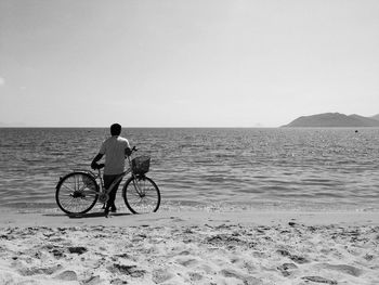 Rear view of man riding bicycle on beach