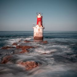 Lighthouse by sea against sky