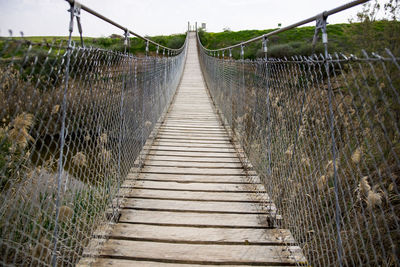 Wooden footbridge on land against sky