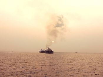 Ship sailing on sea against sky during sunset