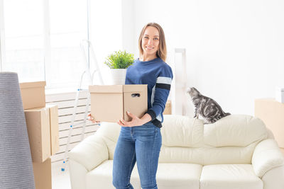 Portrait of smiling young woman sitting on sofa at home