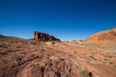 Rock formations on landscape against clear blue sky