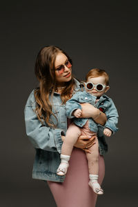 Portrait of young woman wearing sunglasses against black background