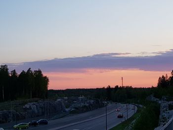 Cars on road against sky during sunset
