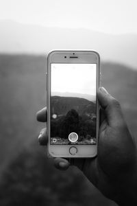 Close-up of hand holding smart phone against clear sky