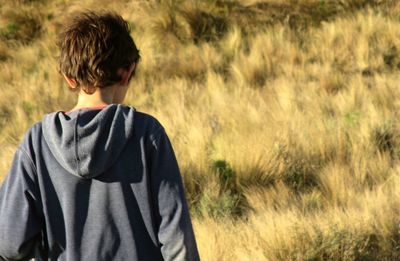 Rear view of boy standing on field