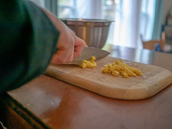 Cropped hands of person cutting food on board at home