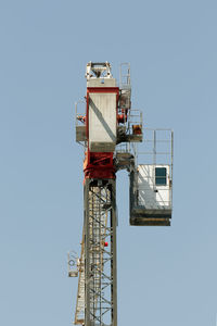 Low angle view of crane against clear blue sky