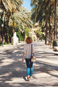 Rear view of woman walking on footpath