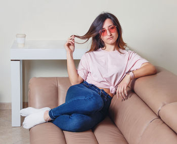Portrait of young woman wearing sunglasses sitting at home