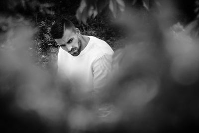 Portrait of young man against blurred trees