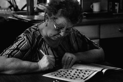 Senior woman writing in newspaper while sitting at home