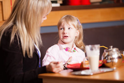 Mother and girl sitting on table