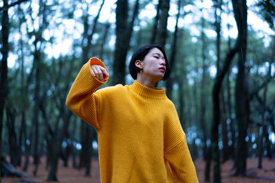 Mid adult woman standing by tree in forest