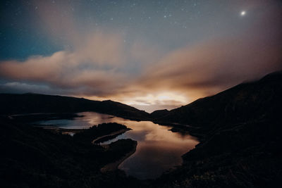 Scenic view of lake against cloudy sky at night