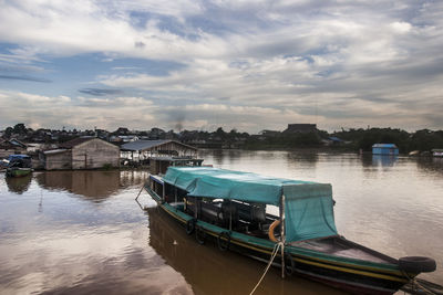 Boats moored on lake by buildings against sky