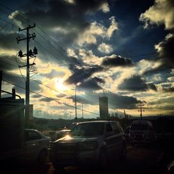 Cars on road against cloudy sky