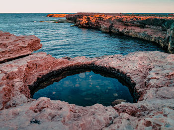 Scenic view of rock formation in sea against sky