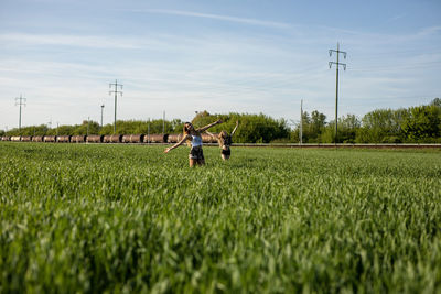 Friends enjoying on grassy field against sky