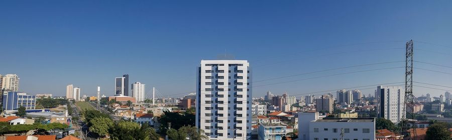 Modern buildings in city against clear blue sky