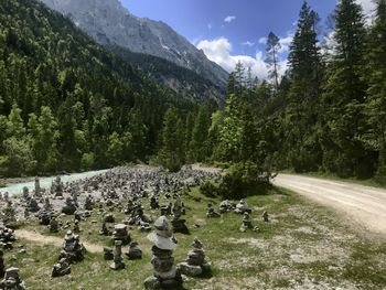 Stacked rocks on field against mountains during sunny day