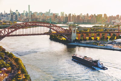 High angle view of ship sailing towards bridge over river against skyline