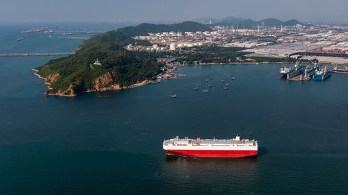 Roll-on roll-of ship loading new cars line up . automotive container carriers floating in sea,