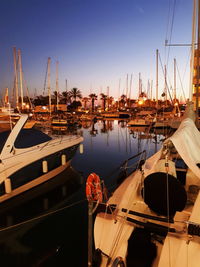 Sailboats moored on harbor against clear sky