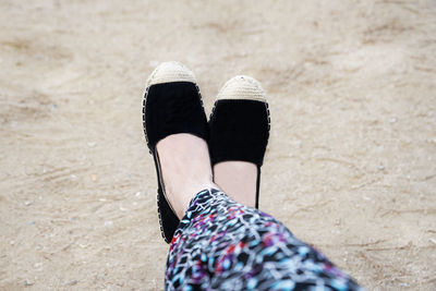 Low section of woman wearing shoes on beach