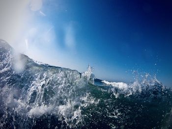 Panoramic view of sea waves splashing against blue sky