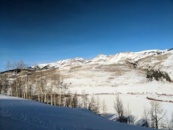 Scenic view of snowcapped mountains against clear blue sky