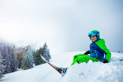 Man skiing on snow covered landscape against clear sky