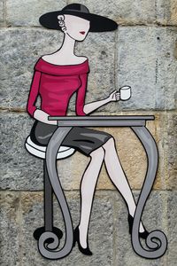Close-up of woman sitting on seat against wall
