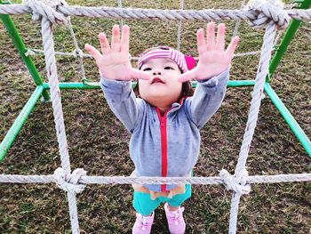 Baby girl standing amidst jungle gym at playground