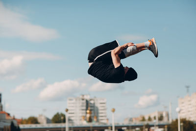 Woman jumping in city against sky