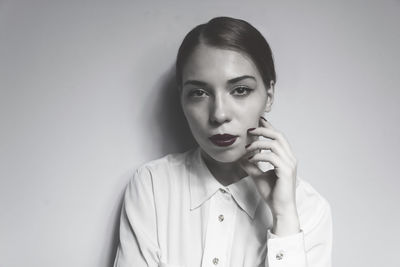 Portrait of young woman standing against wall